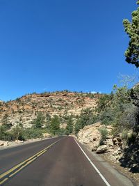 Road by mountain against clear blue sky