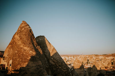Rock formations in city against clear sky