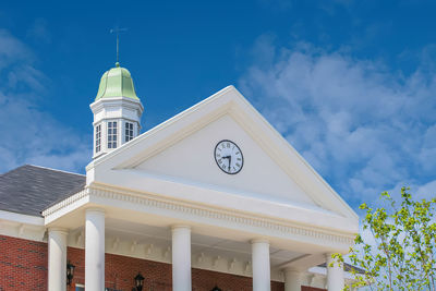 Low angle view of clock tower amidst buildings against sky