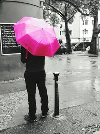 Full length of man with umbrella standing on wet street