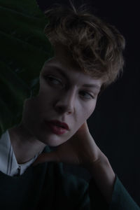 Close-up portrait of young woman against black background