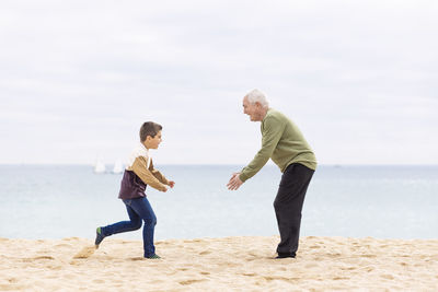 Happy boy running to hug his grandfather on the beach