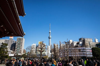 People standing by senso-ji against clear blue sky