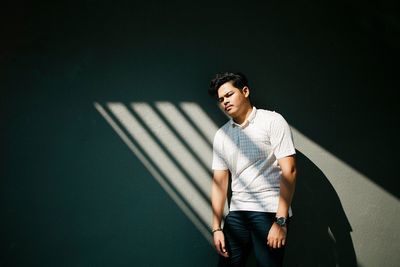 Portrait of young man standing against wall