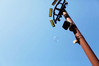 Low angle view of hand photographing against clear blue sky