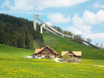 Built structure on field by houses against sky