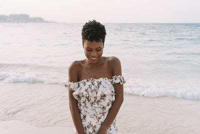 Mid adult woman looking down while standing at beach