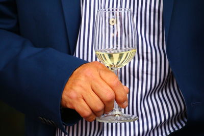 Midsection of man holding wineglass