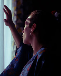 Side view of woman looking through window