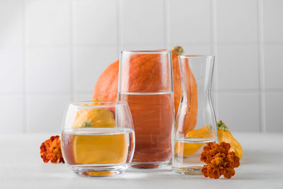 Autumn still life of pumpkins distorted through water in glasses. 