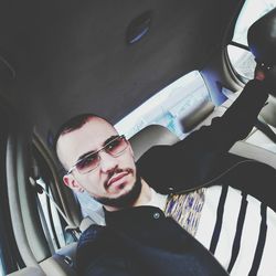 Portrait of young man wearing sunglasses in car