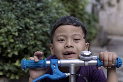 Close-up portrait of boy holding bicycle handlebar