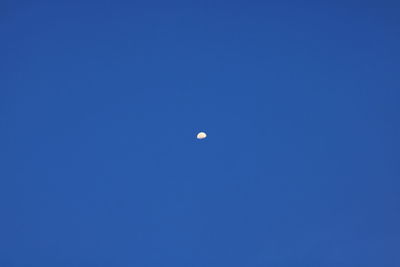 Low angle view of moon against blue sky at night