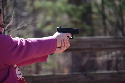 Side view of woman aiming with handgun