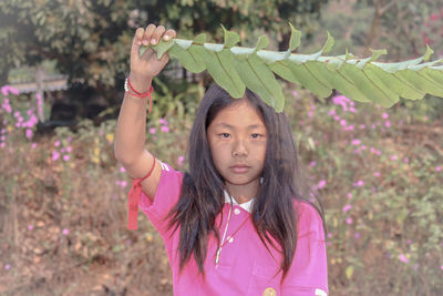 Portrait of a girl with pink petals standing outdoors