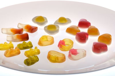 Close-up of multi colored candies in plate against white background