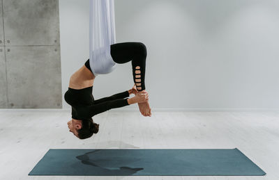 Full length of ballet dancer hanging on textile at gym