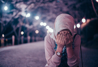 Midsection of person with umbrella on street at night