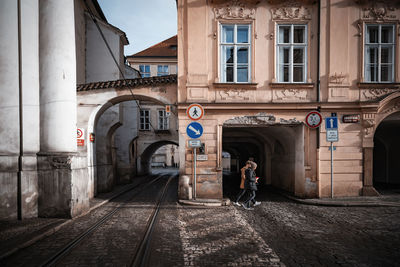 Rear view of woman walking on street amidst buildings