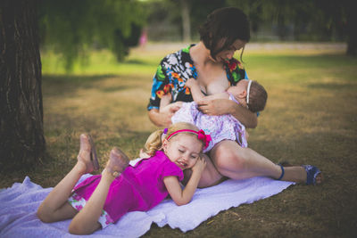 Full length of mother and girl sitting on grass