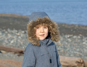 Portrait of boy standing at beach during winter
