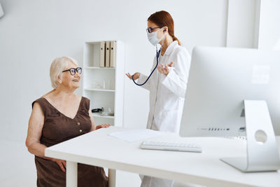 Woman using phone while sitting on table