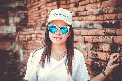 Portrait of smiling young woman against wall