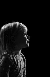 Side view of boy against black background