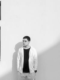 Portrait of young man standing against wall