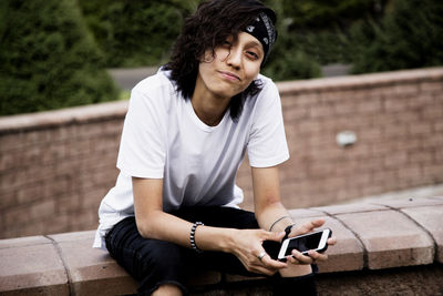 Young man using mobile phone while sitting outdoors