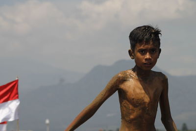 Close-up of boy standing against sky