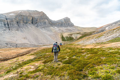 Rear view of man climbing on mountain against sky