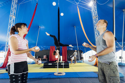 Male and female jugglers practicing with sports ball at circus