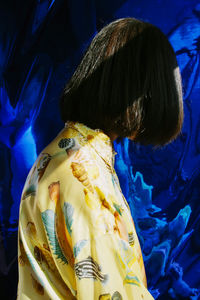 Rear view of woman against blue wall