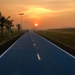 Road passing through landscape at sunrise