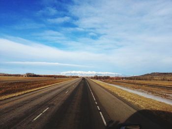 Road amidst field against sky