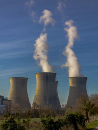 Smoke emitting from factory against sky