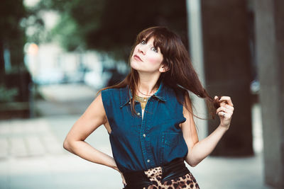 Beautiful woman with hand in hair standing against blurred background