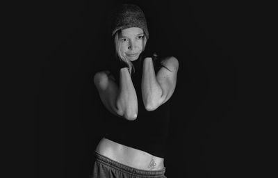 Woman with hand on cheeks standing against black background