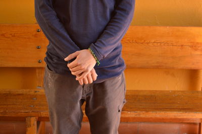 Midsection of man standing against wooden plank