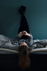 Rear view of woman using mobile phone on bed