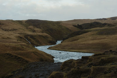 Scenic view of river by mountains against sky