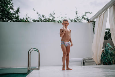 Full length portrait of shirtless man standing in swimming pool