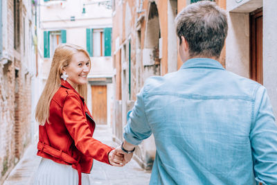 Couple holding hands while standing against buildings