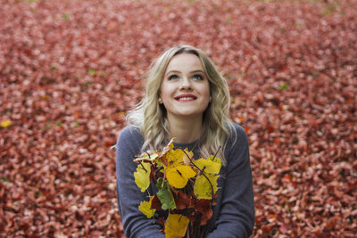 Smiling woman holding leaves during autumn