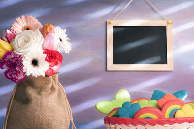 Close-up of colorful food by flowers against blackboard on wall