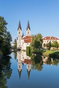 Reflection of church in lake against clear blue sky