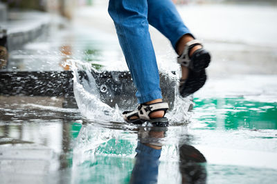 Low section of person splashing water walking on road