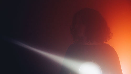 Low angle view of silhouette woman standing on street at night