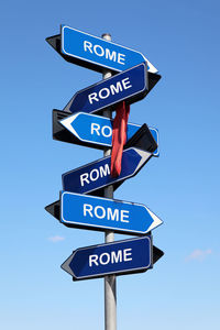 Low angle view of road sign against clear blue sky